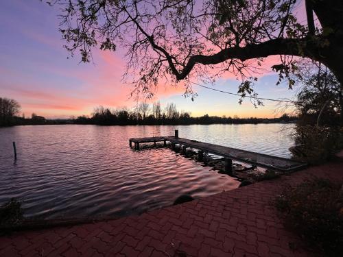a dock on a lake with a sunset in the background at La Belle Vue Du Lac - SPA in Ardres