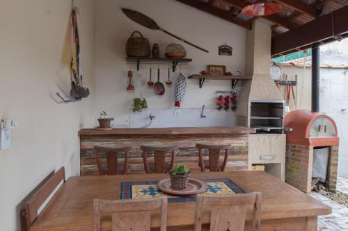 eine Küche mit einem Holztisch und einigen Stühlen in der Unterkunft Suite Casal Mar e Lua em casa compartilhada in Ubatuba