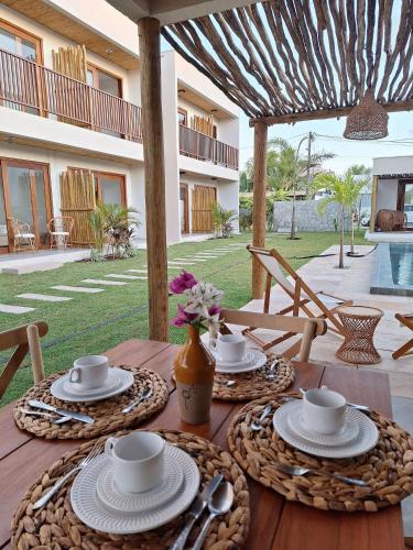 una mesa de madera con tazas y platillos. en Pousada Oasis dos Ventos - São Miguel do Gostoso, en São Miguel do Gostoso