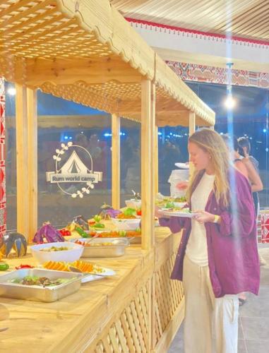 a woman holding a plate of food at a buffet at RUM WORLD BUBBLE lUXURY CAMP in Wadi Rum
