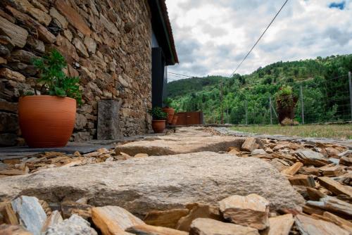 a stone building with potted plants and a pile of rocks at Casa da Eira Velha in Chaves