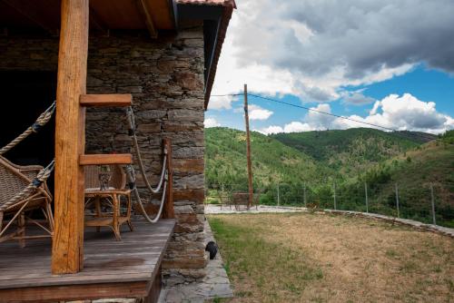 a porch of a log cabin with a chair and a view at Casa da Eira Velha in Chaves