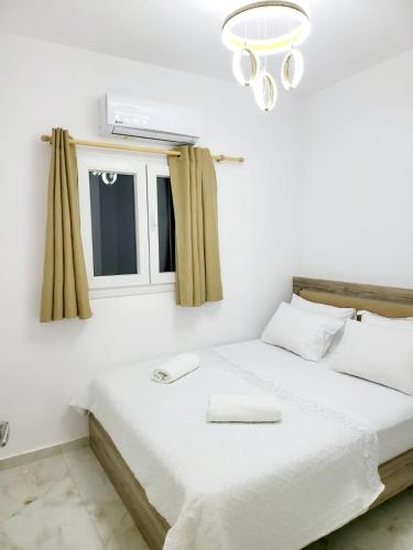 a white bedroom with a bed with a chandelier at AHAMED GREEK SMPCO in Athens