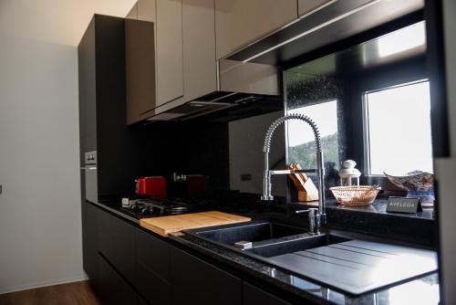 a black kitchen with a sink and a window at Casa da Eira Velha in Chaves