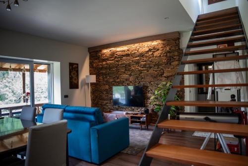 a living room with a blue couch and a stone wall at Casa da Eira Velha in Chaves