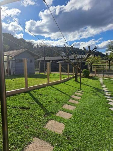 a wooden fence in a yard with a tree at Sítio das Flores - 4 quartos - 8 a 10 pessoas in Garibaldi