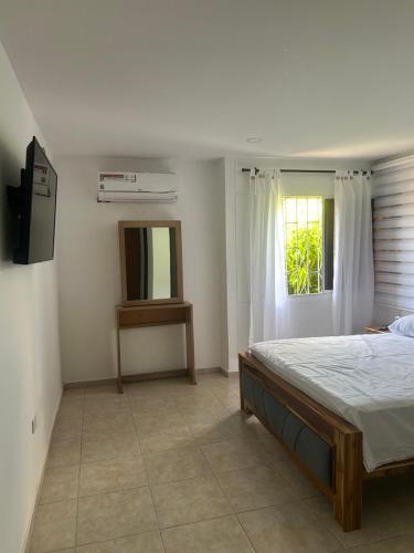 a bedroom with a bed and a television and a window at Casa frente al centro comercial in Montería