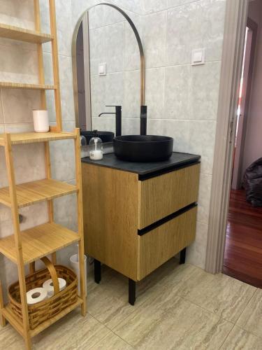 a bathroom with a black sink and a shelf at Appartement avec terrasse in Santoña