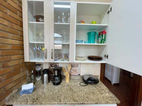 a kitchen with white cabinets and a counter top at Caribean Praia das Toninhas - A 100 metros da areia 21A in Ubatuba