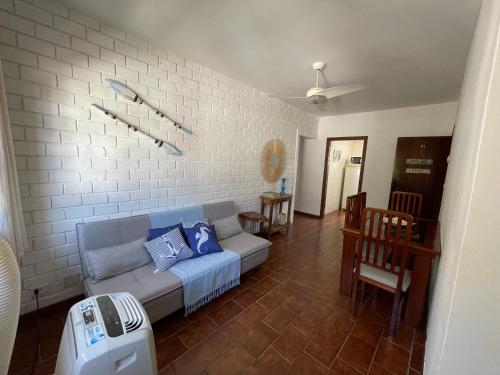 a living room with a couch against a white brick wall at Caribean Praia das Toninhas - A 100 metros da areia 21A in Ubatuba