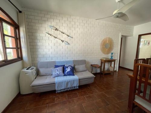 a living room with a couch and a brick wall at Caribean Praia das Toninhas - A 100 metros da areia 21A in Ubatuba