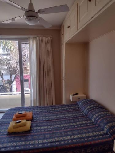 a bedroom with a bed with a blue comforter and a window at DEPARTAMENTo CÉNTRICO in Lobos