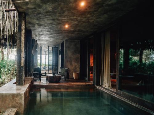 a house with a pool of water in a room at Nômade Temple Tulum in Tulum