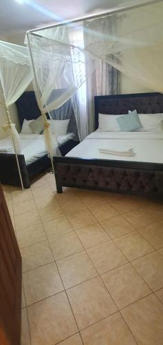 two beds with mosquito nets in a room at Shukrey palace 2 in Nakuru
