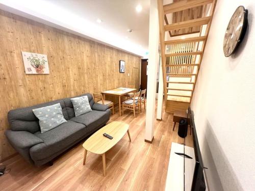 a living room with a gray couch and a wooden floor at Sunrise house JU in Osaka