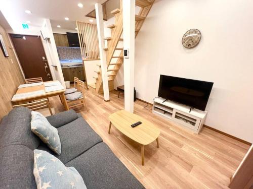 a living room with a couch and a flat screen tv at Sunrise house JU in Osaka