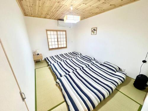 a bedroom with a striped bed in a room at Sunrise house JU in Osaka