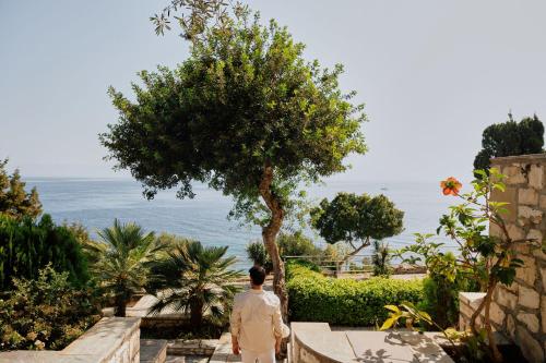 a man is looking out at the ocean at Agali Hotel Paxos in Gaios