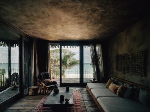 a living room with a couch and a large window at Nômade Temple Tulum in Tulum