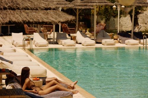 two women laying on lounge chairs next to a swimming pool at Agali Hotel Paxos in Gaios