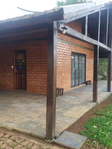 a brick building with a large patio with a door at Casa de Campo Rancho Bodaneze in Abelardo Luz