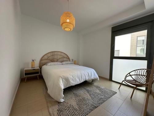 a bedroom with a bed and a chair and a window at Apartamento Jardín de Cano - Preferente familias y mayores de 25 años in El Puerto de Santa María