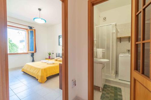 a bedroom with a bed and a bathroom with a sink at Holiday home in Alghero 44952 in Alghero