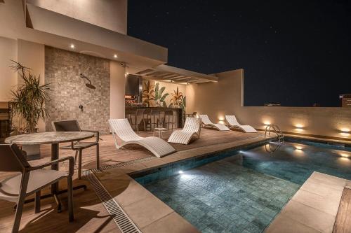 a swimming pool with chairs and a table next to a building at HOUZE - Stay & Residences by AVA in Asuncion