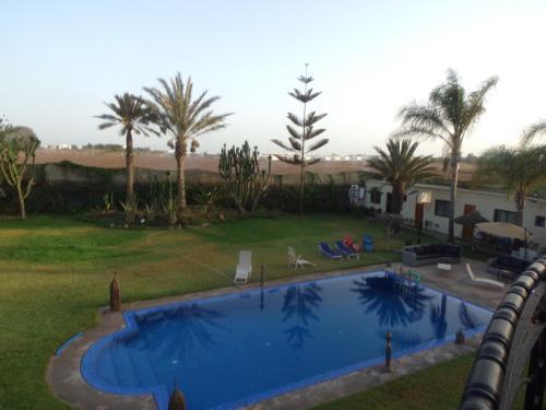 a swimming pool in a yard with palm trees at Jnane Ville Verte in Casablanca