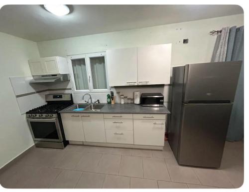 una cucina con mobili bianchi e un frigorifero in acciaio inossidabile di Cozy Apt a Koolbaai