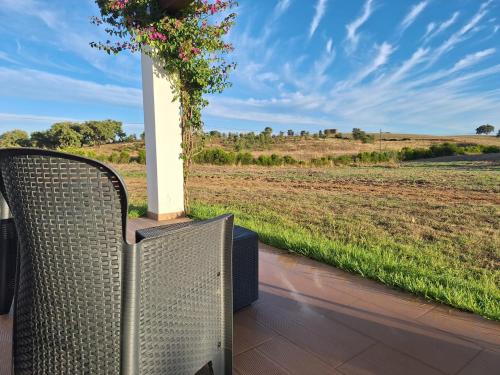 two wicker chairs sitting on a porch looking out at a field at Monte da Isabel in Vale de Água