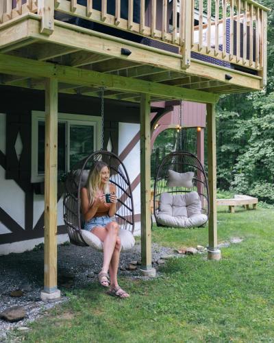 a woman is sitting in a porch swing at Iron Gate Chalet - 5 Minutes to Smugglers Notch! in Cambridge