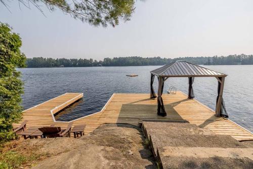ein Holzsteg mit einem Pavillon auf einem See in der Unterkunft Muskoka Lakeshore Cottage Bliss in Gravenhurst