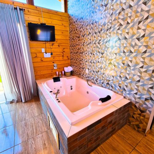a large bath tub in a bathroom with a tv at Cabanas Colina Do Sol in Cambará