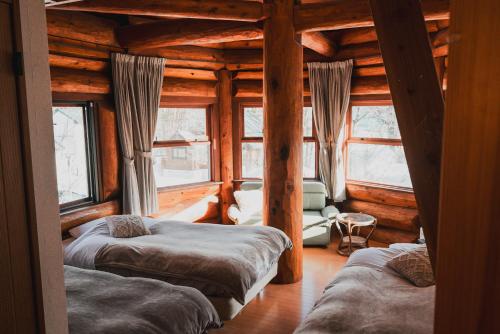 a room with three beds in a log cabin at Hakuba Pension & Log Hotel Meteor in Hakuba