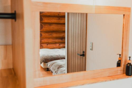 a mirror with a reflection of a bed in a room at Hakuba Pension & Log Hotel Meteor in Hakuba