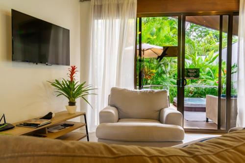 a living room with a chair and a television at Bukala Village Lodge in San Ramón