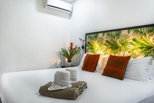 a bedroom with a white bed with towels on it at Bukala Village Lodge in San Ramón