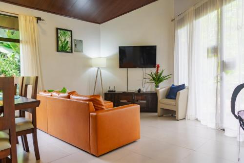 a living room with an orange couch and a tv at Bukala Village Lodge in San Ramón