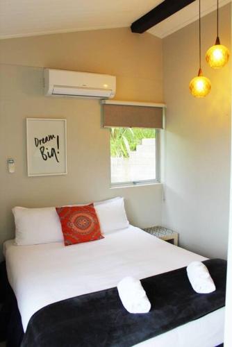 a bedroom with a white bed and a window at Bobs Haven - Long Bay Coromandel in Coromandel Town