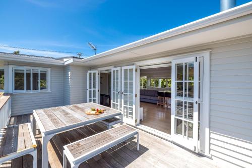 a deck with a table and benches on a house at Aloha Cottage with Pool & Spa, Waiheke in Oneroa