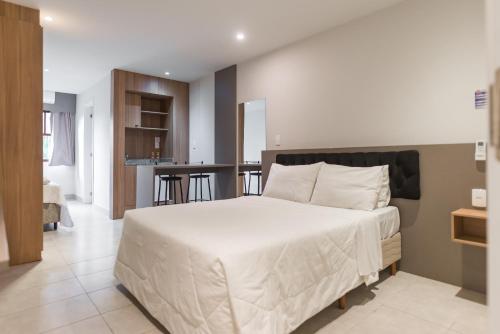 a bedroom with a large white bed and a kitchen at Hotel Vila Suíça 1818 in Nova Friburgo