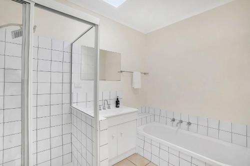 un bagno bianco con vasca e lavandino di Cottage on James circa 1855 a Port Fairy