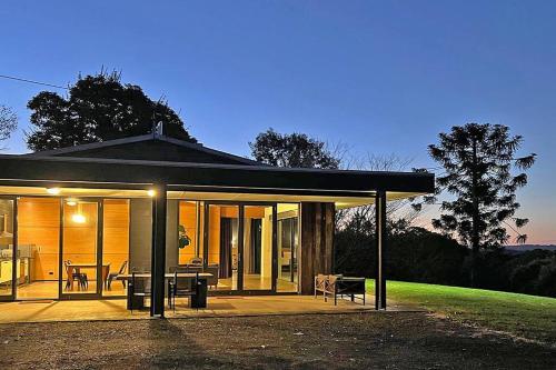 a house with a patio and a table on a lawn at Upper House in Maleny