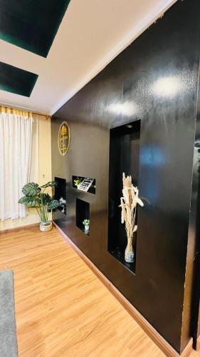 a living room with black walls and a wooden floor at Homestay by Tas in Kulai