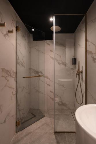 a bathroom with a glass shower with a sink at Cube Social Boutique Capsule Hotel at Boat Quay in Singapore