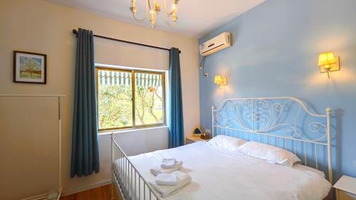 a bedroom with a bed with a blue headboard and a window at Cloud Tree Inn Boutique Guesthouse XiChong DaPeng ShenZhen 深圳大鹏西涌云树里民宿Yun Shu Li in Shenzhen