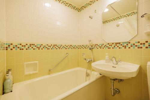 a bathroom with a sink and a bath tub and a sink at Hotel Monterey Sendai in Sendai