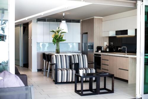 a kitchen with a island with chairs and a table at Seahaven Noosa Beachfront Resort in Noosa Heads