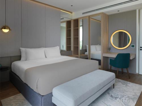 a bedroom with a large white bed and a desk at La Green Hotel and Residence in Bang Tao Beach
